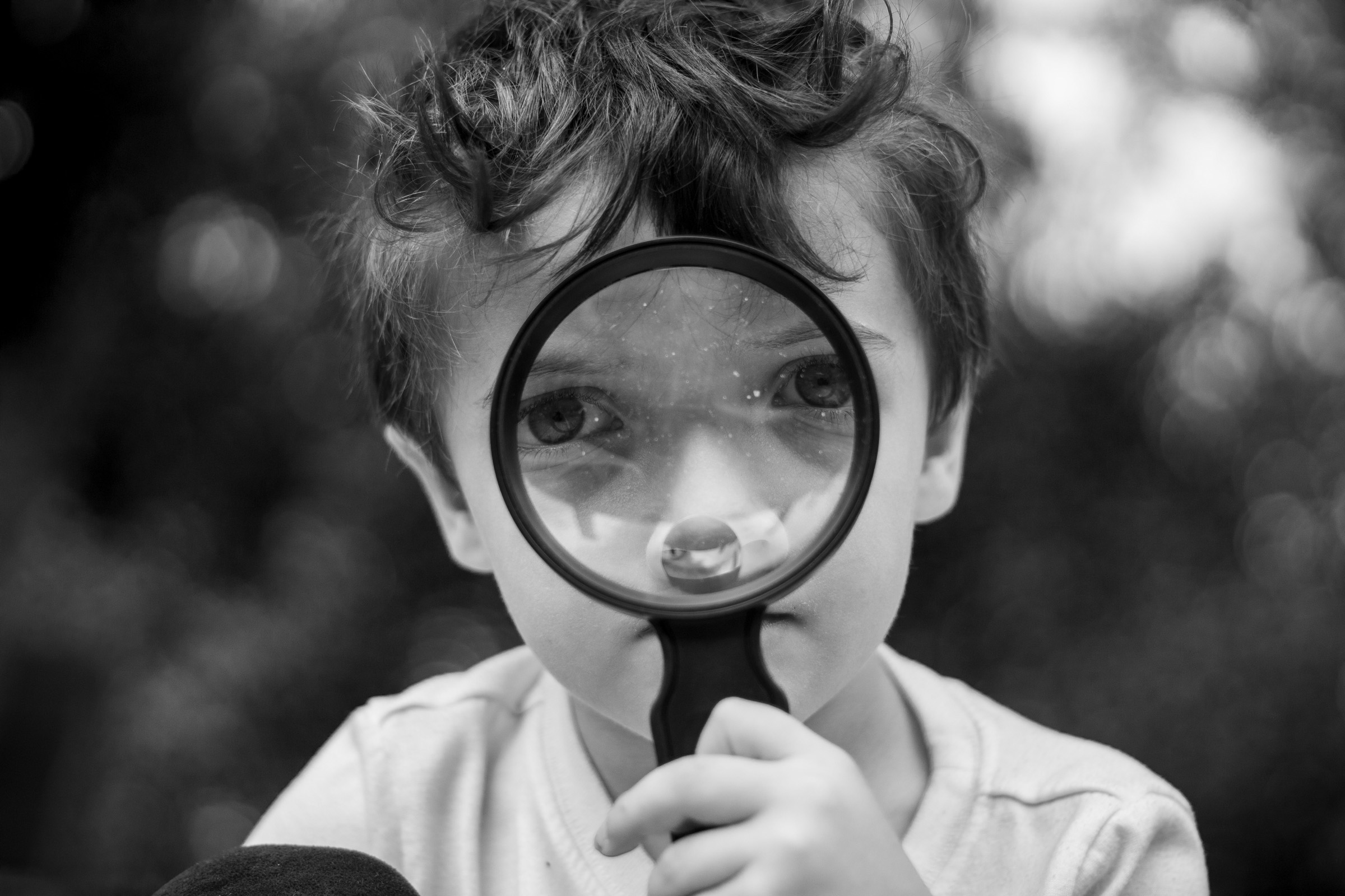 He looks through a magnifying glass, turning an ordinary moment into a closer look at the world around him.